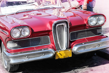 Old and rusty red american cars of 1950s (rented) in Havana, Cuba. Edsel Pacer with front view with caucasian woman as a driver. Outdoors, sunny day, copy space. Retro / vintage car.