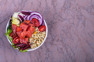Poke bowl trand. Raw fish, rice and halhy vegetables on wooden background