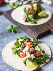 Tortillas with vegetables and white fish. Avocados, tomatoes, red onions and cod pieces sprinkled with sesame and lime juice in tortillas. Mexican food.