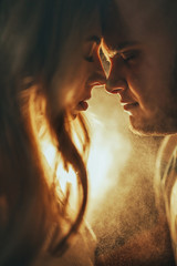 Portrait of the young couple in love standing face to face against the light of the lamp. © Stanislav