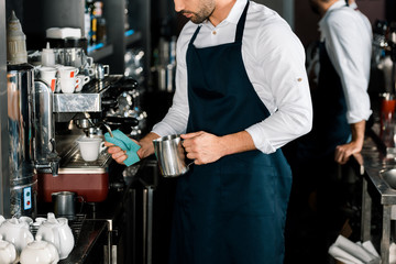 cropped view of barman in apron preparing coffee with coffee machine