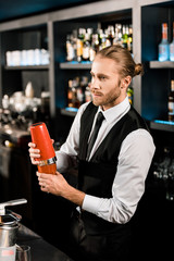 Handsome barman mixing cocktail in shaker