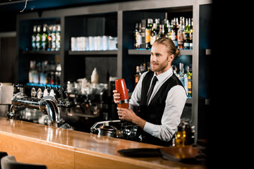 Handsome barman mixing drink in shaker