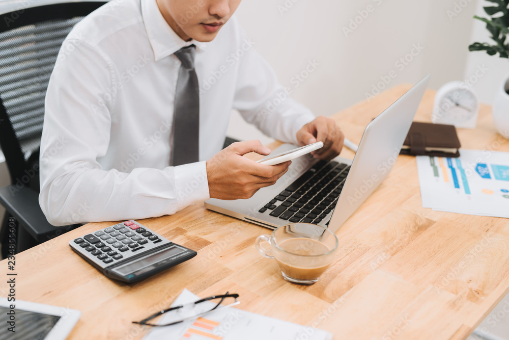 Poster business man busy working on laptop computer and using mobile smart phone in modern office, close up