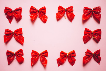 Christmas red satin bows frame, set of ribbons on pink background