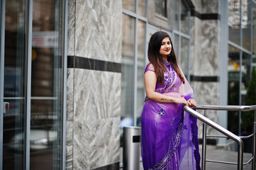 Indian hindu girl at traditional violet saree posed at street.