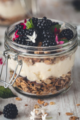 Petit Déjeuner Sain avec des Granola ou Muesli, des Mûres, yaourt à la Noix de Coco et Fleurs Comestibles