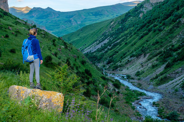 Girl with a backpack in a mountain valley.