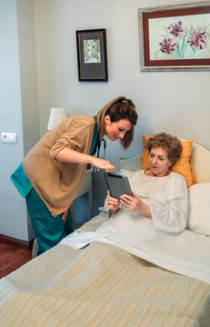 Female doctor showing results of a medical test on the tablet to female senior patient