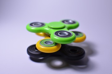 Three fidget spinners, green, yellow, black