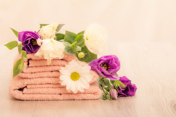 Fototapeta na wymiar Stack of soft terry towels with flowers on wooden boards