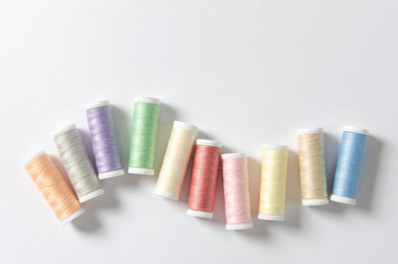 Multicolor thread coils on white background, sewing, pattern. Top view