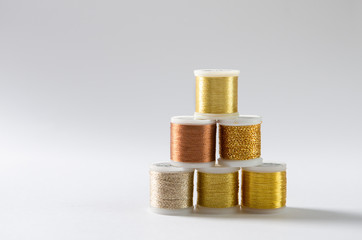 Golden thread coils on white background, sewing, place for text. Top view