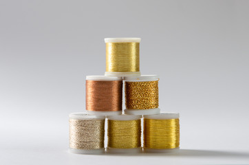 Golden thread coils on white background, sewing. Top view