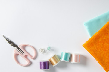 Scissor, buttons, thread and fabrics on white background. Copyspace