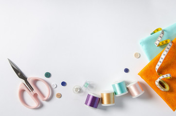 tailor's tools - scissors, measuring tape, threads, fabric - on white background. Copy space