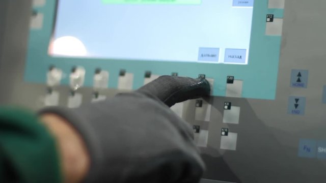 Human hand pushing buttons on industrial equipment. Worker controll production