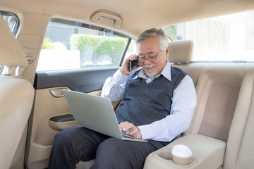 Business senior rich man Stock trader player in suit working with laptop computer and using a smart phone in his car , concept for senior business success
