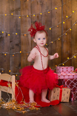 Christmas scene of baby girl posing with presents in studio shoot. Happy smile child celebrating new year holiday.