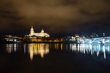 Fototapeta premium Cityscape at night with a cathedral and bridge illuminated and reflected in the river