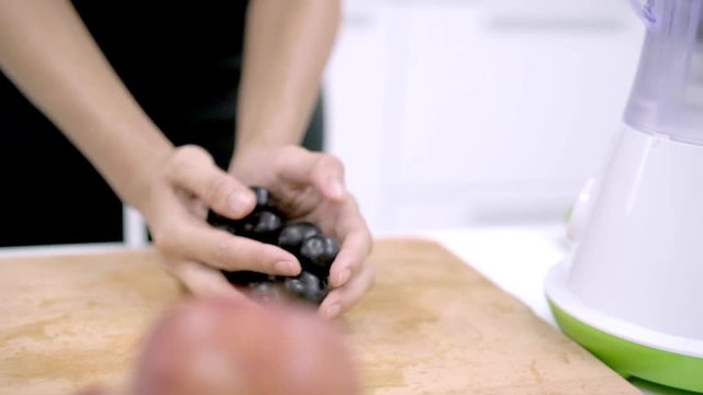 Slow motion - Sporty Asian woman using blender to make grape juice in the kitchen, beautiful female in sport clothing use organic fruit lots of nutrition herself at home. Healthy food concept.