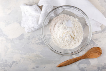 White and whole grained flour with a baking powder in a glass bowl.