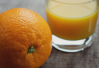 One whole orange with a glass of fresh orange juice