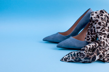 Blue suede stilettos and a scarf. On a blue background. Women's elegant shoes. Free space for text....