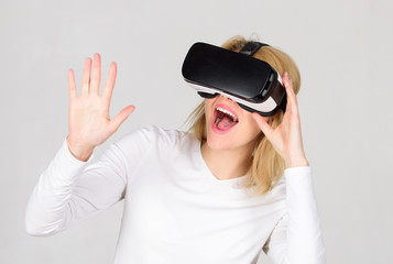 Woman wearing virtual reality goggles in grey background. Woman using virtual reality headset. Confident young woman adjusting her virtual reality headset and smiling. Woman with VR.