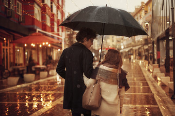 Couple in love on the street on a rainy day. Friends walking down the street
