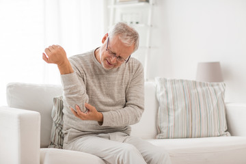 people, health care and problem concept - unhappy senior man suffering from elbow pain at home