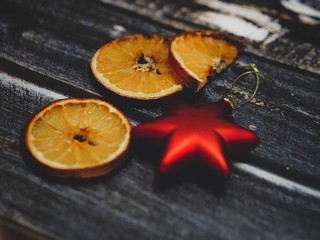 Dried festive orange slices and Christmas tree toys lie on a dark wooden table in rustic style