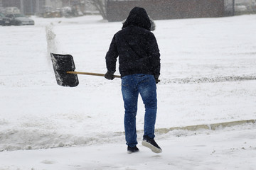 cleaning snow with shovel in winter day