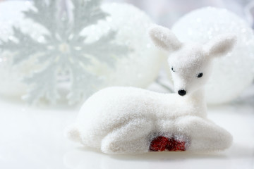 Small white deer and christmas decorations  background.