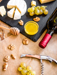 bottle of red wine, appetizers and corkscrew on wooden backgroun