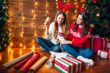 Sisters kneeling on floor and choosing christmas decorations