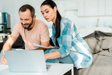 beautiful couple doing paperwork and using laptop at home