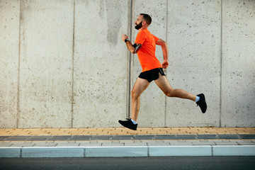 Young bearded man running on the street. Healthy lifestyle concept.