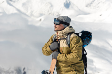 Fototapeta na wymiar Man standing with the snowboard on the snowy mountains