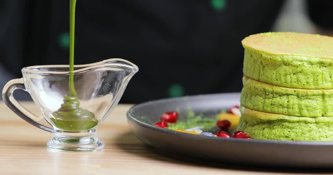 Pouring green macha syrup into little glass for preparing cake