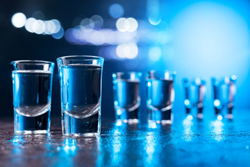 Glasses of Vodka lit with blue backlight. - obrazy, fototapety, plakaty
