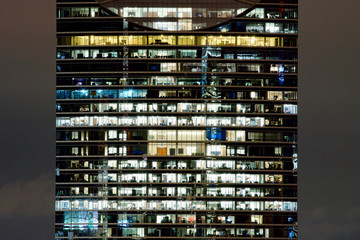 Fototapeta na wymiar Symmetrical windows in an office building at night