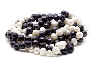 Two strands of white and black pearls intertwined on white background isolated