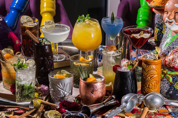 Whiskey-cola cocktail, mojito-cocktail, orange cocktail, strawberry cocktail in glass glasses with straws. Bar accessories: shaker, spoon, spices on a wooden stand