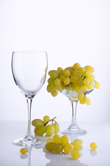 Glass and a bunch of ripe grapes on white background