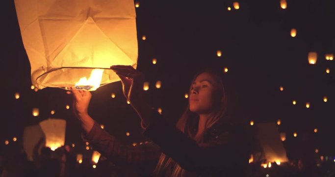 Happy young woman holding lit paper lantern at night during lantern festival 