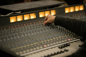 Audio engineer operating mixing console with hands