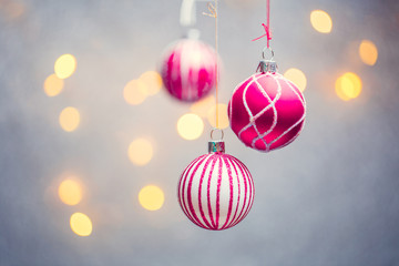 Picture of three Christmas pink balls with pattern on gray background with lights.