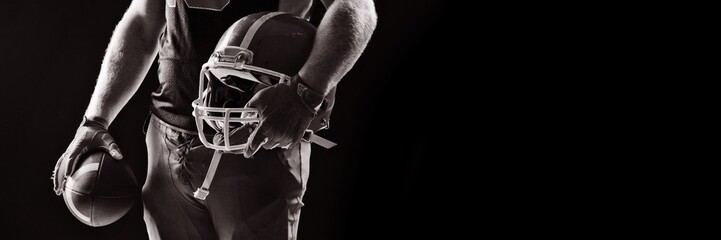 American football player standing with helmet and rugby ball - Powered by Adobe