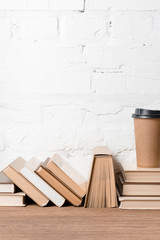 books and disposable coffee cup on wooden table